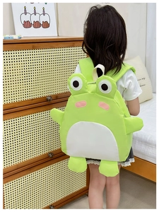 Rear view of child wearing the cute green 3D frog backpack in a warm bedroom setting