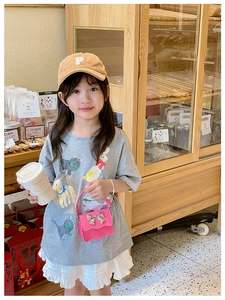 Pink mini crossbody bag with silver bow and metal chain shown on a child model