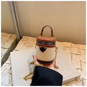 Detail einer Mini-Zylindertasche mit Kettenriemen und braunem Leder-Farbblocking