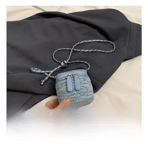 Détail du mini sac en jean bleu clair avec clous argentés, matelassage et bandoulière