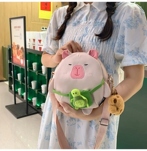 Detail of pink capybara cartoon shoulder bag with 3D ears and green turtle charm