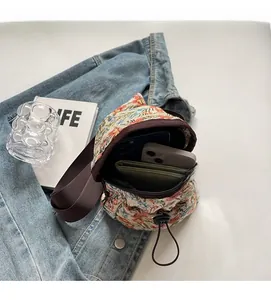Détail du sac bandoulière fleuri montrant un intérieur spacieux pour portables et portefeuille