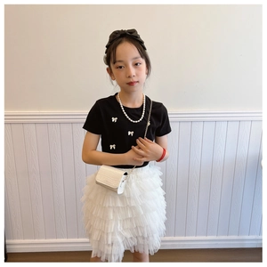 Detail of girls black t-shirt with 3D bows and layered white tulle mesh skirt