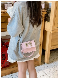 Rear view of a pink girls' crossbody bag with silver bow and wave edge detail
