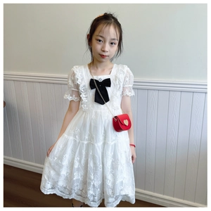 Detail of red heart-shaped chain bag paired with white lace floral embroidery dress
