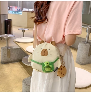 Detail of plush Capybara crossbody bag with turtle backpack and matching charm on strap