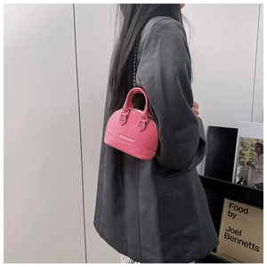Detail of pink shell-shaped mini bag showing leather texture and silver chain strap