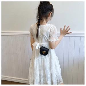 Detail of a black heart-shaped crossbody bag styled with a white lace princess dress