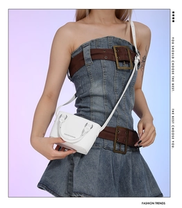 Detail of white mini crossbody bag with textured faux leather and embossed logo