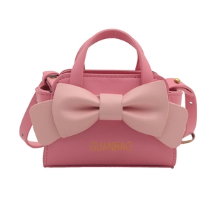 Pink crossbody bag for children featuring a large bow and adjustable shoulder strap