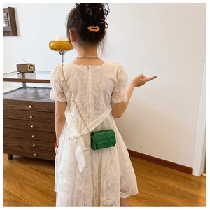 Detail of green faux crocodile skin mini crossbody bag with golden chain on child model