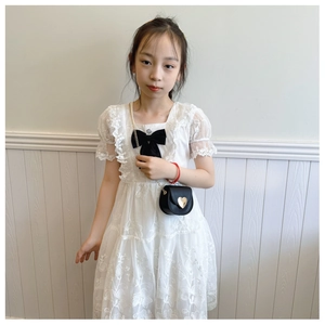 Close-up of a white lace princess dress featuring a black bow and a heart-shaped chain bag