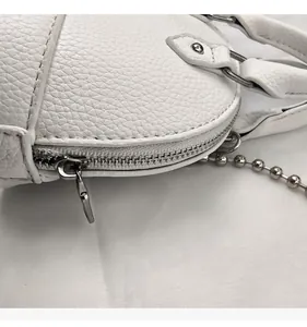 Detail of silver smooth metal zipper on white pebble leather mini shell bag