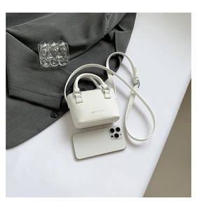 Size comparison of a white lychee leather mini handbag with a smartphone