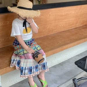 Mädchen Sommeroutfit mit weißem T-Shirt, kariertem Rock und kleiner brauner Umhängetasche