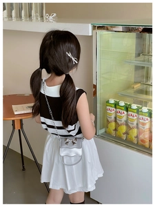 Girl wearing a silver metallic mini crossbody bag with a bow and chain strap in a cafe