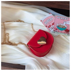 Detail of red leather saddle bag with gold heart buckle and metal chain strap