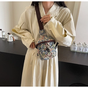Détail du sac bandoulière en toile florale avec poche avant à cordon et sangle brune