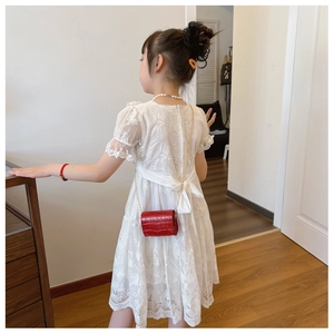 Detailed back view of a white lace party dress with a large decorative bow and red bag