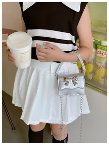 Close-up of a silver metallic mini bag for kids with a large bow and chain strap
