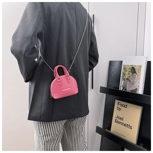 Close-up of mini shell-shaped crossbody bag in pink with elegant metal chain strap