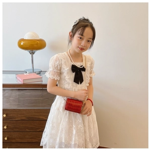Detail of elegant white lace dress with puff sleeves and black bow tie for girls