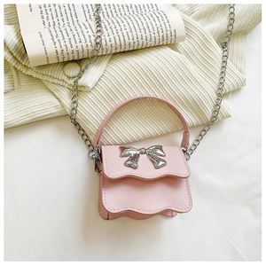 Detail of pink mini kids handbag featuring a silver metal bow and wave-cut edge flap