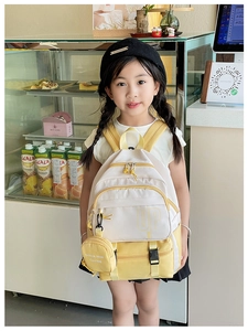 Close-up of yellow and white kids backpack with side mini pouch on girl in a cafe