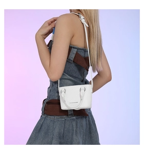 White mini crossbody bag with litchi texture and silver lettering on model