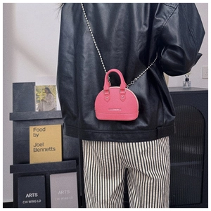 Detail of pink mini shell bag with lychee leather texture and pearl chain strap