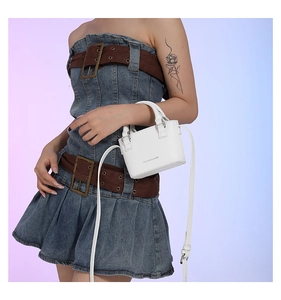 Close-up of a white mini faux leather tote bag with elegant Fashion and Bags lettering