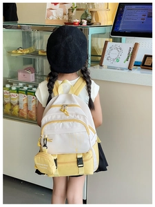 Detail of kids backpack with UP lettering, yellow straps and mini round coin purse