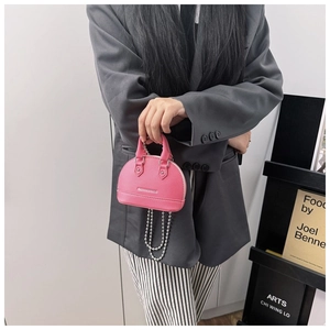 Detail of pink shell crossbody bag with silver FASHION&BAGS logo and chain strap