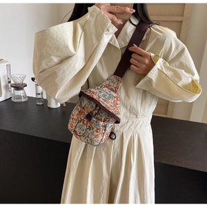 Gros plan sur un sac de poitrine vintage à fleurs avec une bandoulière marron réglable