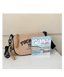 Detail of khaki canvas crossbody bag with bold black lettering and chunky chain strap