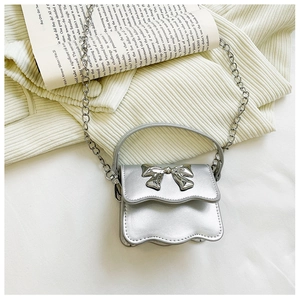 Detail of silver chain bag featuring bow metal clasp and wavy flap edges for kids