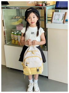 Detail view of children's canvas backpack with yellow and white panels and UP logo
