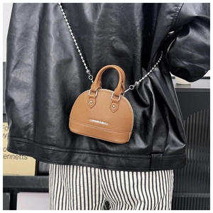 Detail view of brown pebbled leather shell bag with silver chain strap and fashion text