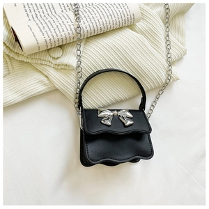 Detail of a black mini crossbody bag with wavy edges and silver bow metal ornament