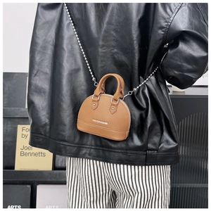 Brown lychee leather mini shell bag with silver chain strap worn cross-body by model