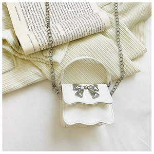 Detail of white mini crossbody bag with wavy flap and silver bow on knit fabric