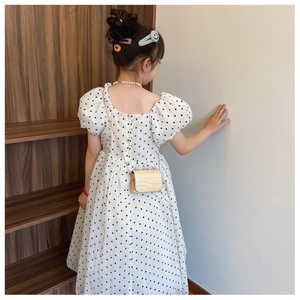 Detail view of the back V-neck design and invisible zipper on the white polka dot dress