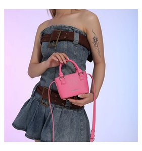 Detail of pink mini tote bag with pebble leather texture and adjustable strap on a model