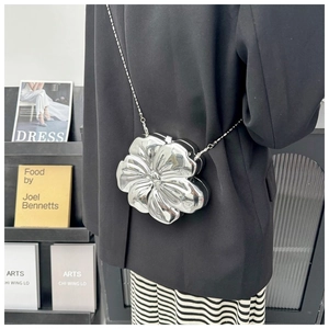Close-up of a silver flower-shaped metallic bag with mirror finish and slim chain