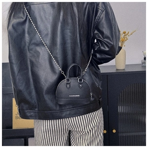 Detail of a mini black shell crossbody bag with litchi grain and silver bead chain strap