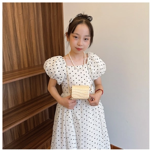 Detailed view of polka dot puff sleeve dress and mini gold crocodile texture chain bag