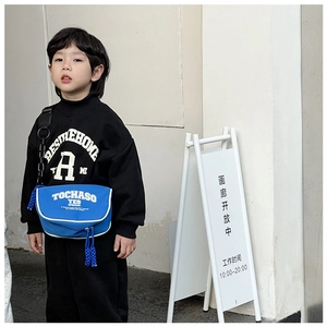 Close-up of blue nylon crossbody bag with white piping and adjustable strap on child model