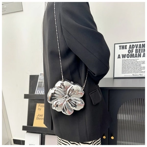 Detailed view of a silver flower-shaped metallic crossbody bag with 3D petals and chain