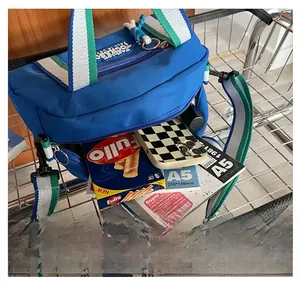 Détail d'un grand sac bandoulière bleu en toile pour enfants contenant un carnet A5