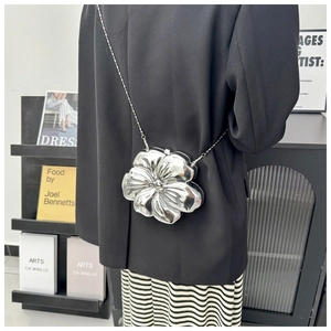 Detailed view of a 3D floral silver metal chain bag shown on a model's shoulder